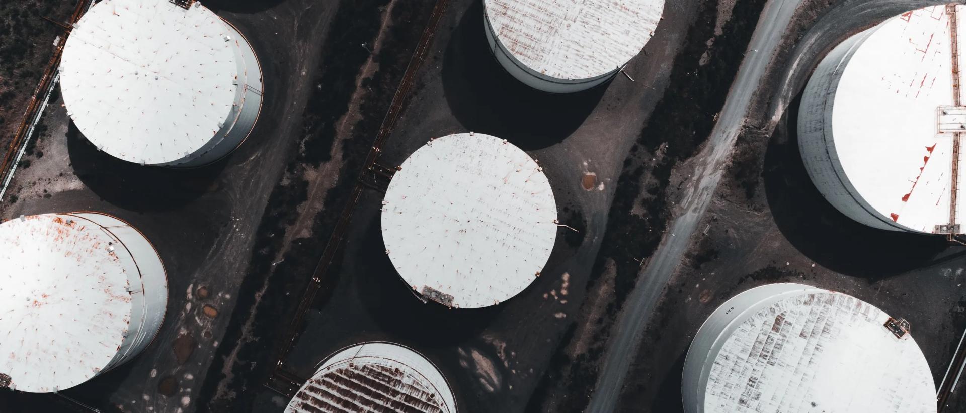 A tank farm from directly above: white tank roofs, access roads and containment between them